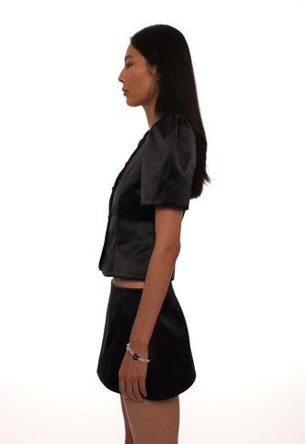 Woman wearing a black satin outfit on a white background