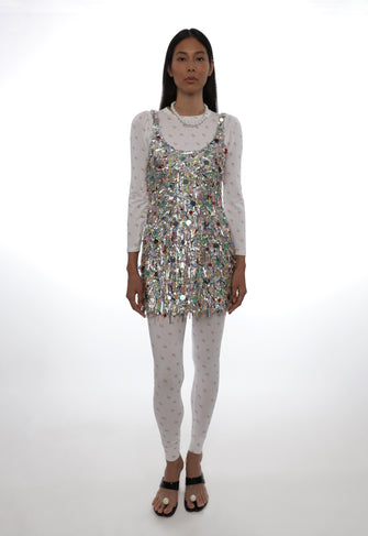 Model wearing a sequin dress over a long-sleeve top and leggings on a white background