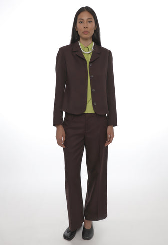 Woman wearing a brown suit with a green shirt on a white background