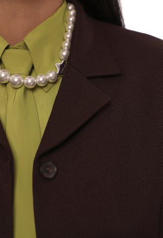 Brown blazer over a green shirt with a pearl necklace