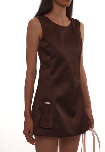 Close up image of brown sleeveless dress with miniature dress attached worn by a model on a white background