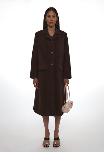 Woman wearing a brown coat and skirt set with a white background
