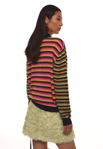 Person wearing a colorful striped sweater and light green skirt on a white background