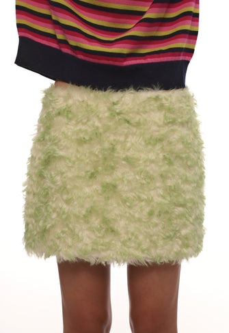 Green fluffy skirt worn with a colorful striped top on a white background