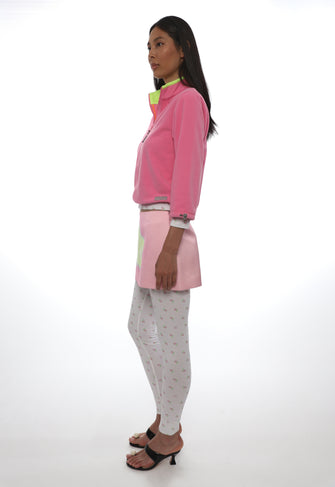 Woman wearing a pink jacket and light gray pants on a white background