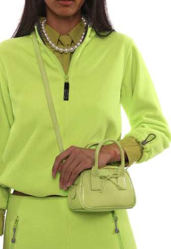 Person wearing a bright green outfit with a matching handbag on a white background