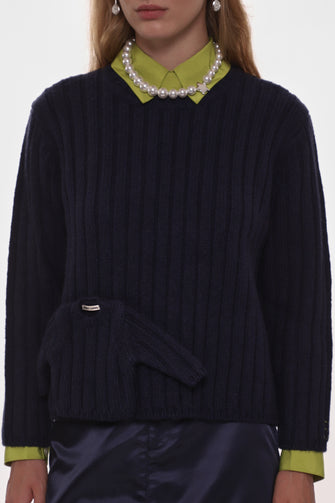Person wearing a dark blue sweater with a green collar and cuffs, on a white background
