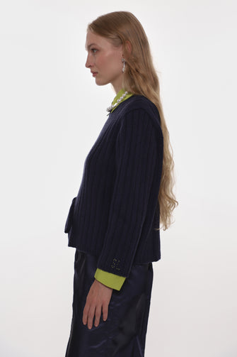 Woman wearing a dark blue outfit with green accents on a white background