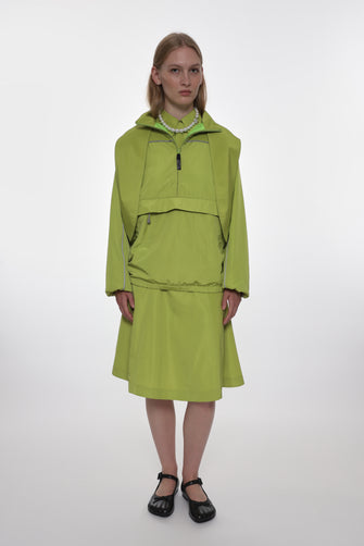 Person wearing a green jacket with matching skirt on a white background