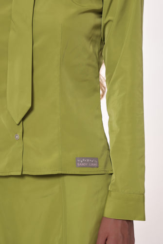 Close up of green shirt with a visible brand label on a white background