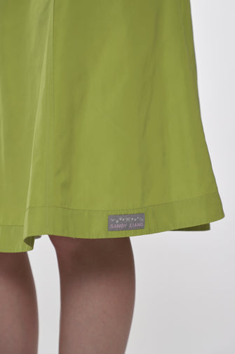 Close up of green skirt with a brand label on a white background