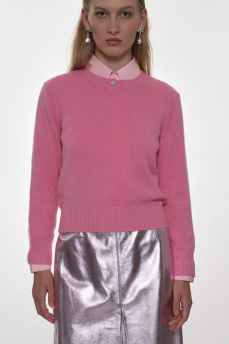 Woman wearing a pink sweater and silver skirt on a white background