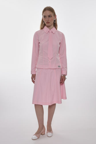 Woman wearing a pink outfit with a shirt and skirt on a white background