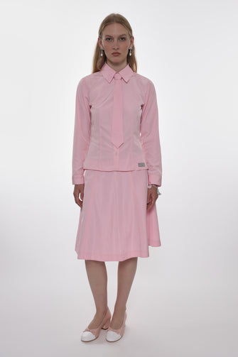 Woman wearing a pink outfit with a shirt and skirt on a white background