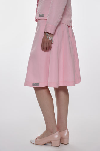 Person wearing a pink skirt and shirt with pink pumps on a white background
