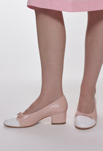 Pink and white shoes worn with a pink skirt on a plain background