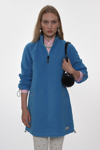 Woman wearing a blue jacket holding a black bag on a white background