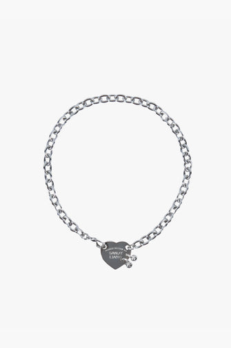 A silver-colored oversized cable chain necklace with a heart tag pendant. The pendant is engraved with the text 'RETURN TO SANDY LIANG'. against a white background