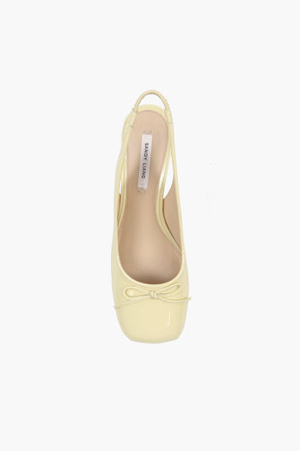 A single yellow patent leather shoe on a white background