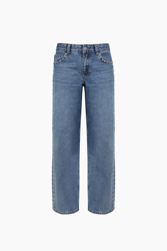 A pair of blue denim jeans with rhinestone rivets at the sides against a white background