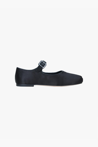 Black satin pointed-toe flat shoe with an adjustable pin-buckle strap and a low stacked heel against a white background