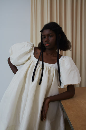 Woman wearing a puff sleeve bridal dress leaning against a wooden table