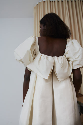 Woman wearing a puff sleeve dress with decorative details at back