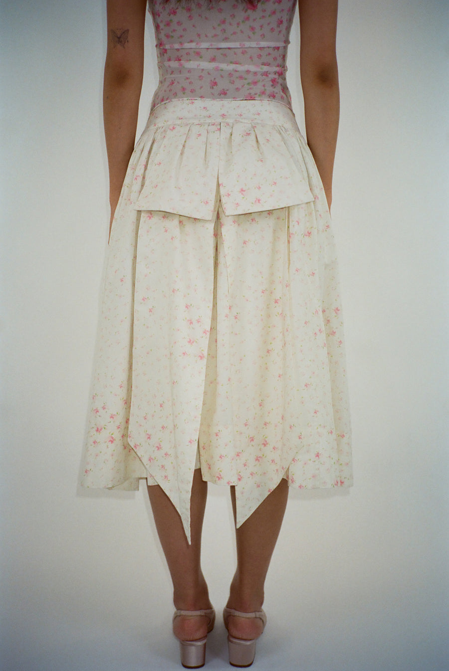 Off white midi skirt with pink floral print and bow at back on model