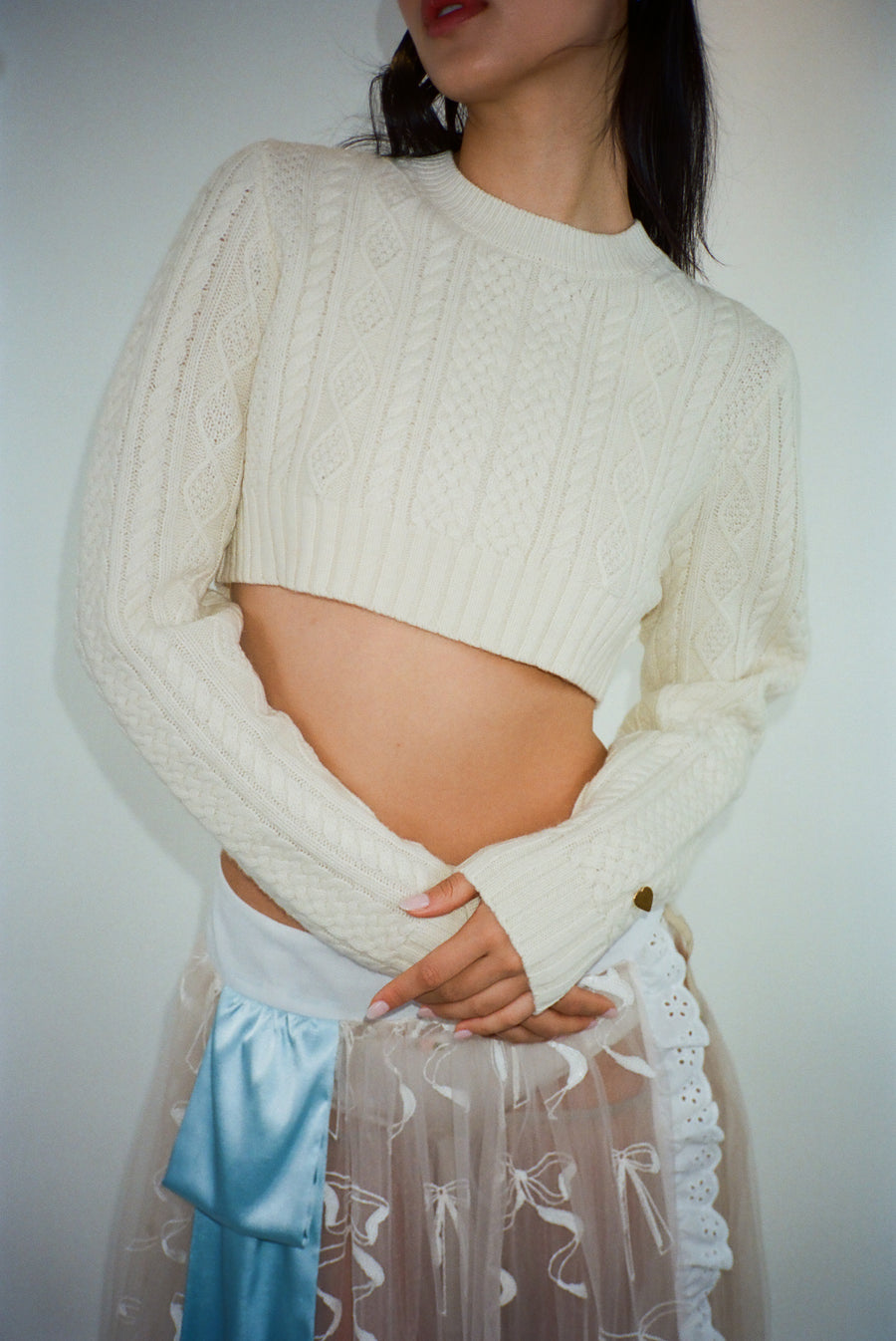 Cropped cable knit sweater in off white on model