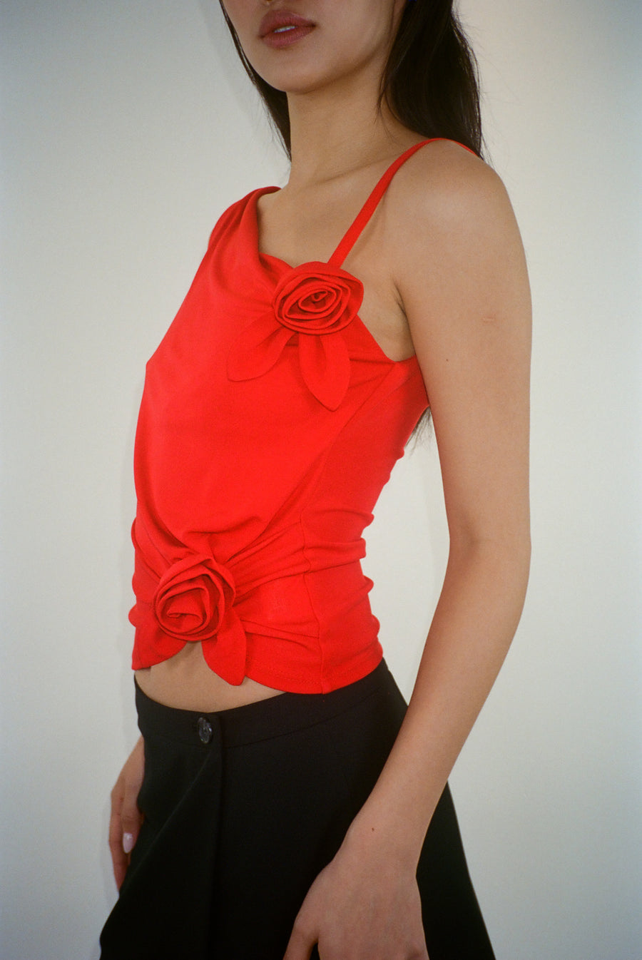 Draped asymmetric tank top in red with rosette details on model