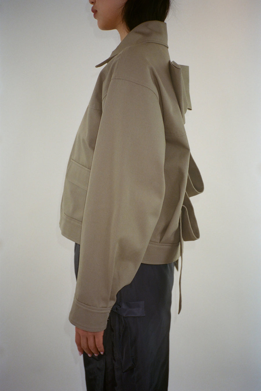 Spread collar jacket in taupe with oversized bow at back on model