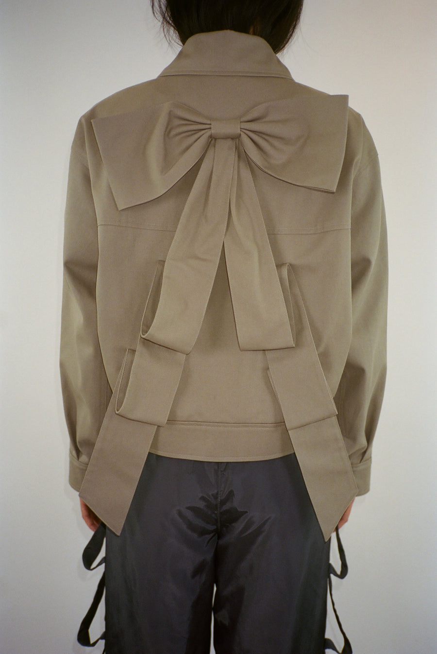 Spread collar jacket in taupe with oversized bow at back on model
