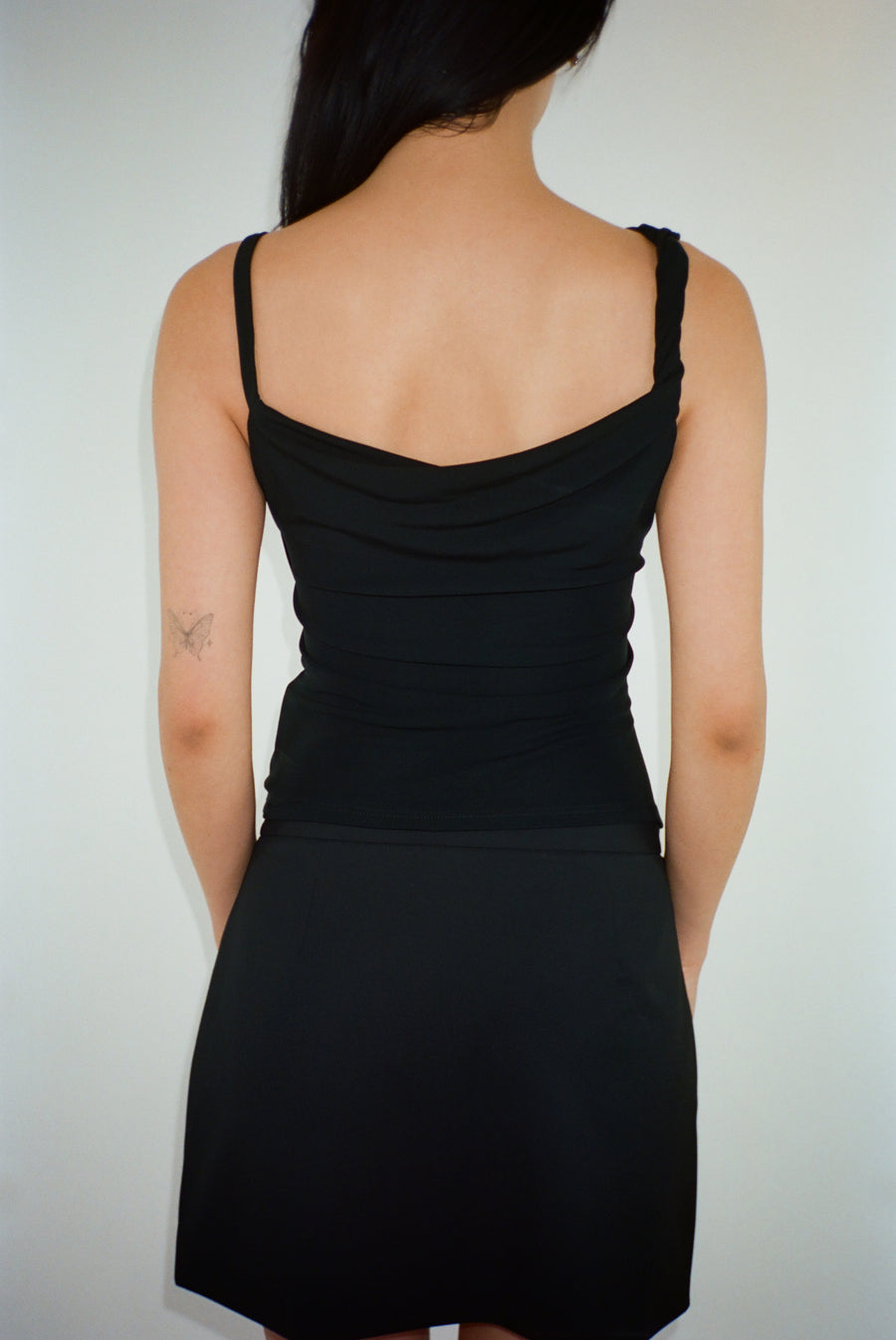 Draped asymmetric tank top in black with rosette details on model