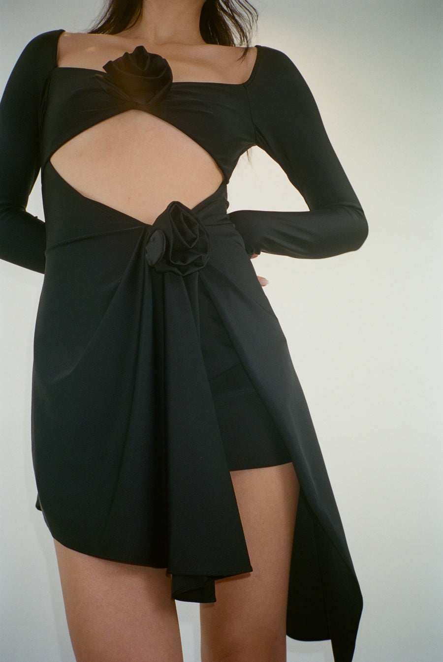 Asymmetric mini dress in black with rosette details on model