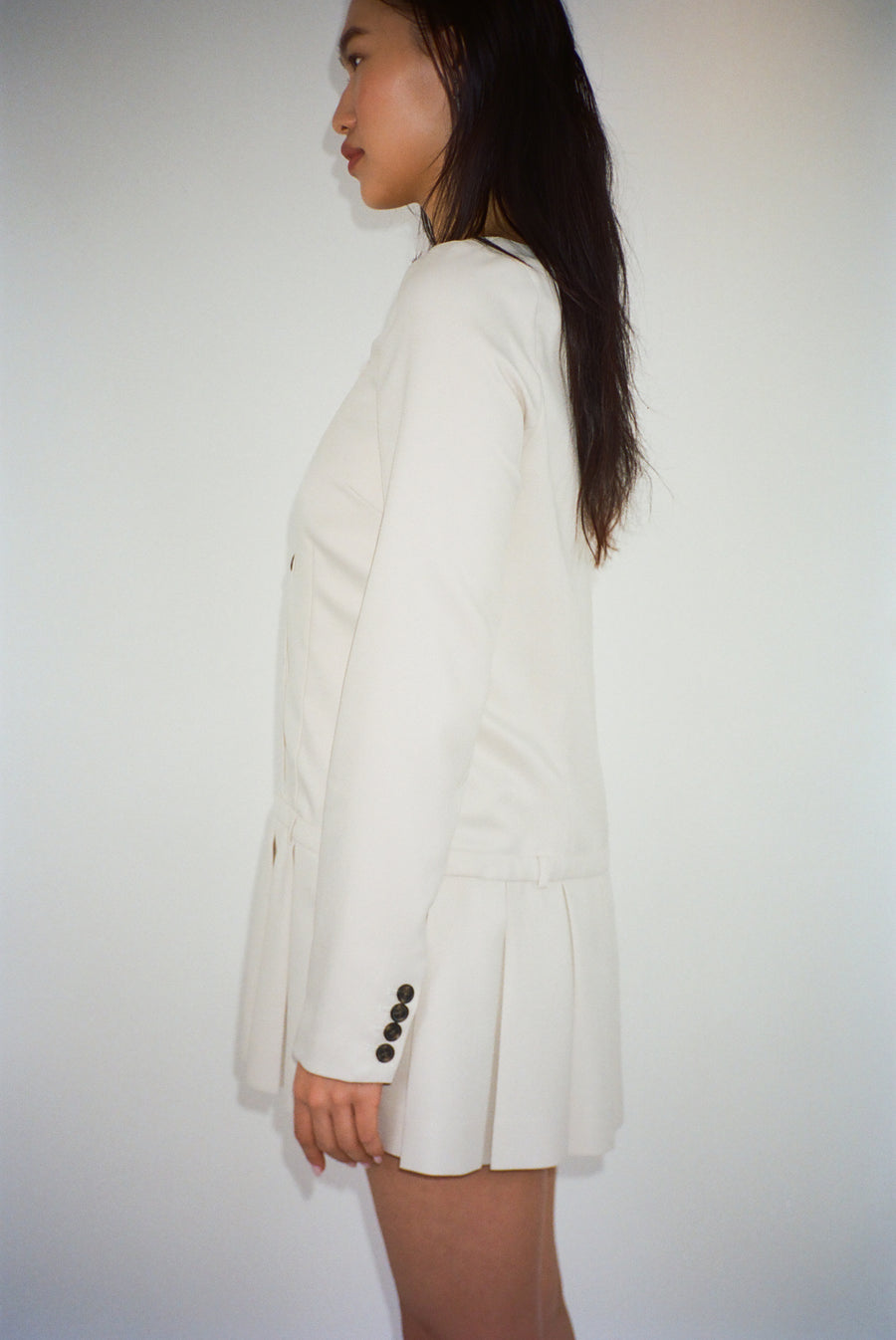 Long sleeve mini dress in off white suting with buttons and pleats on model