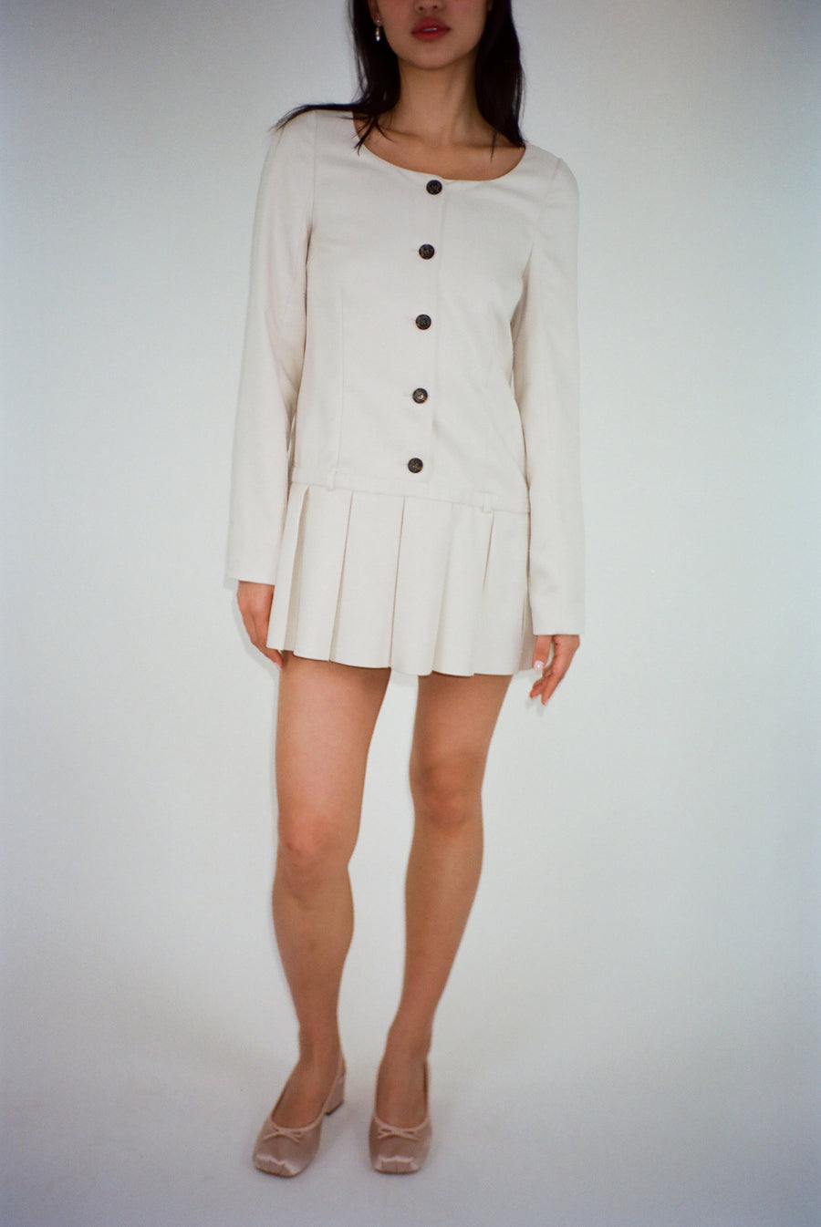 Long sleeve mini dress in off white suting with buttons and pleats on model
