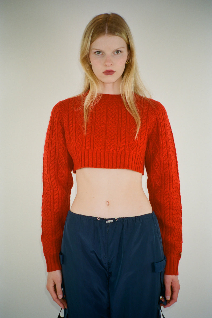 Cropped cable knit sweater in red on model