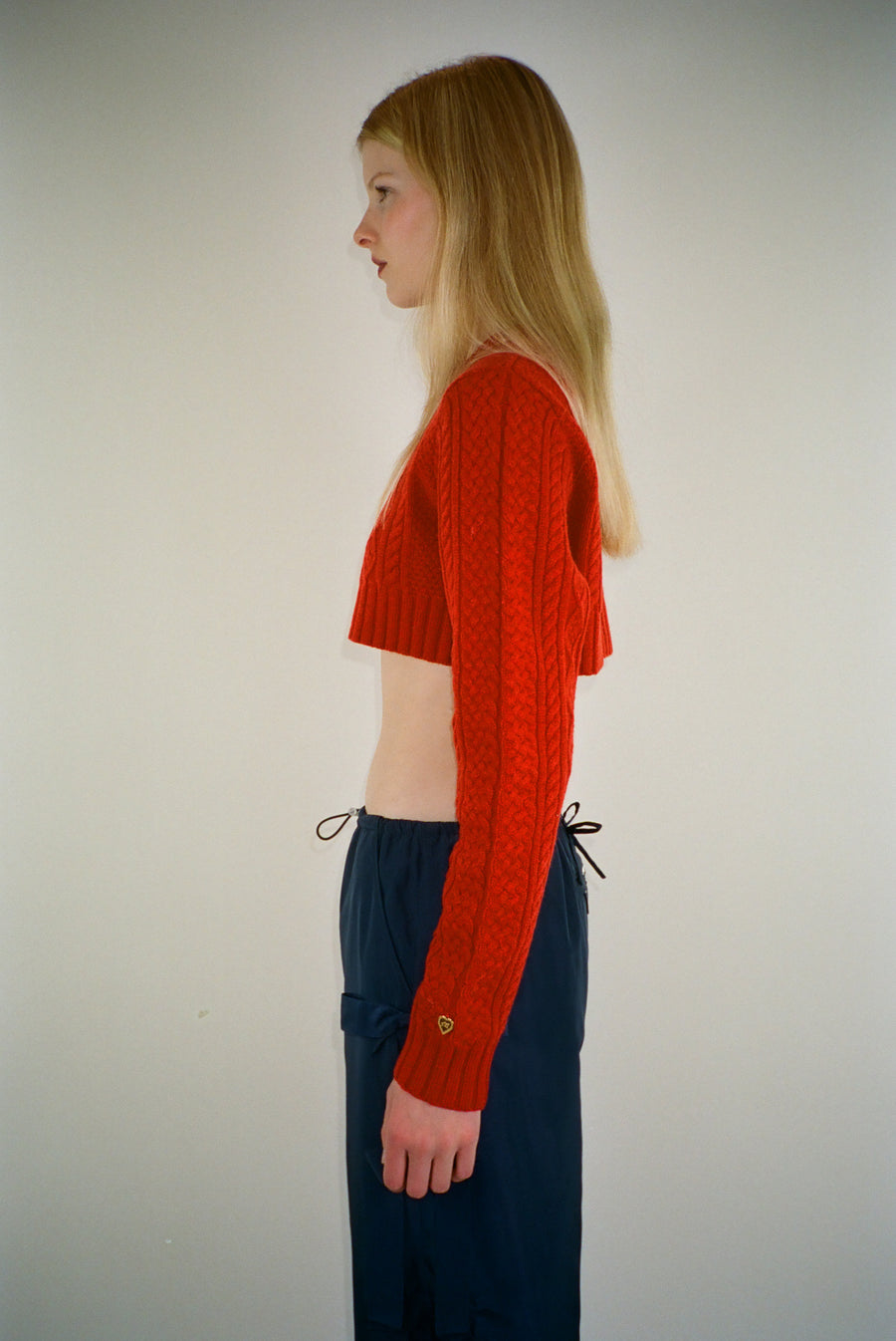Cropped cable knit sweater in red on model