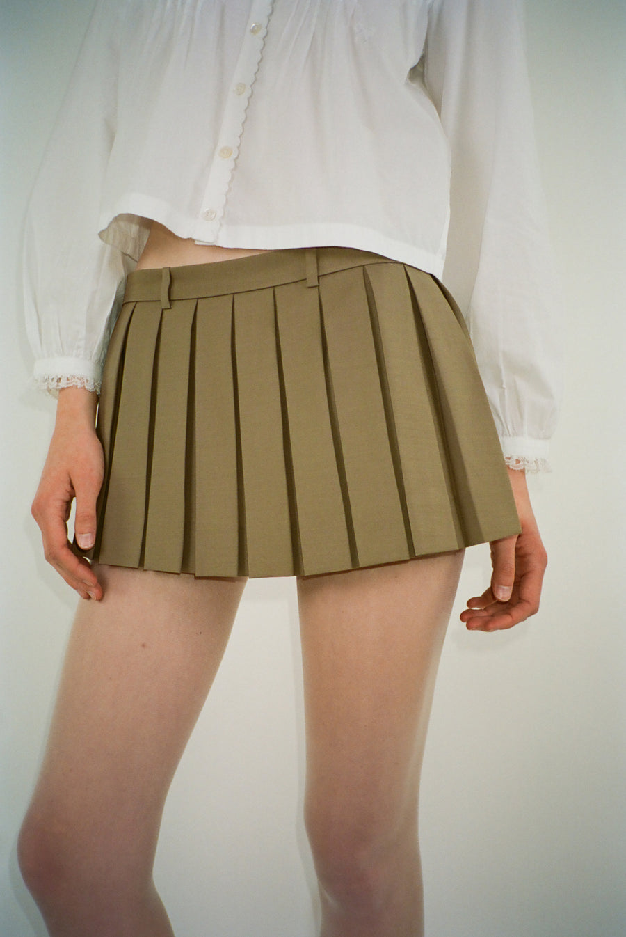 Pleated mini skirt in taupe with eyelet panel at back on model