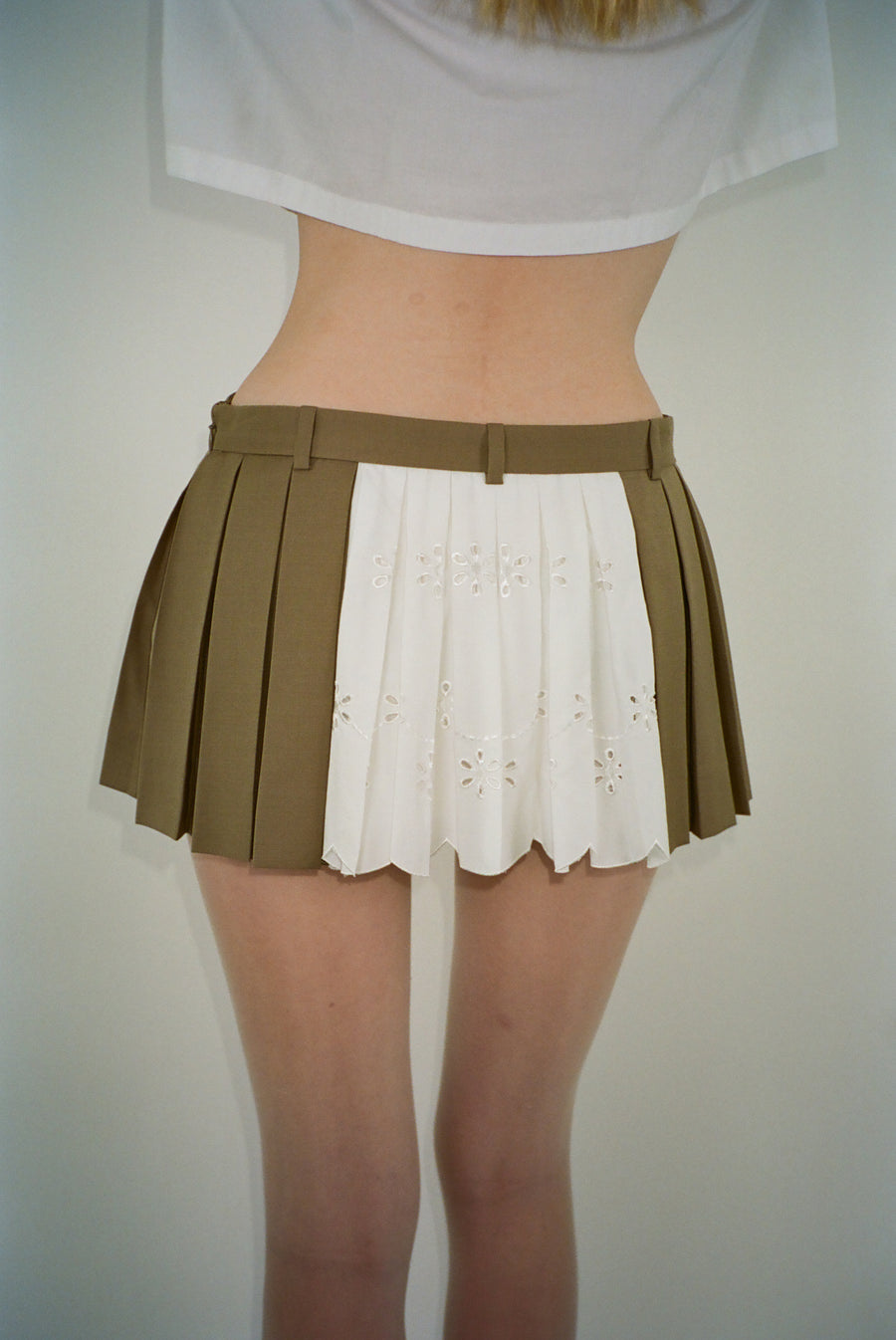 Pleated mini skirt in taupe with eyelet panel at back on model