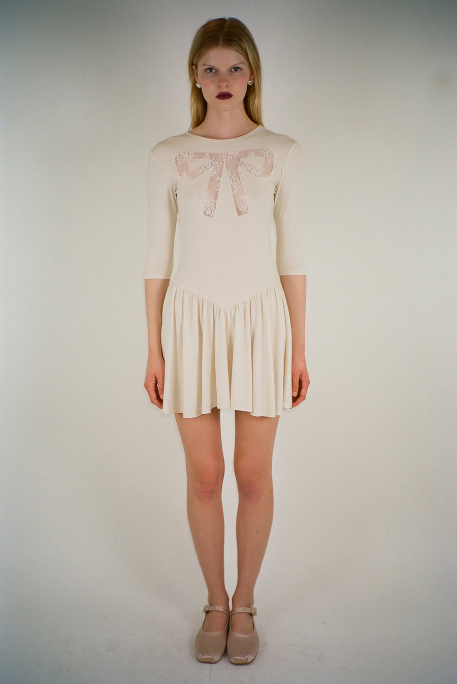 Mini dress in off white with lace cut out bow detail on model
