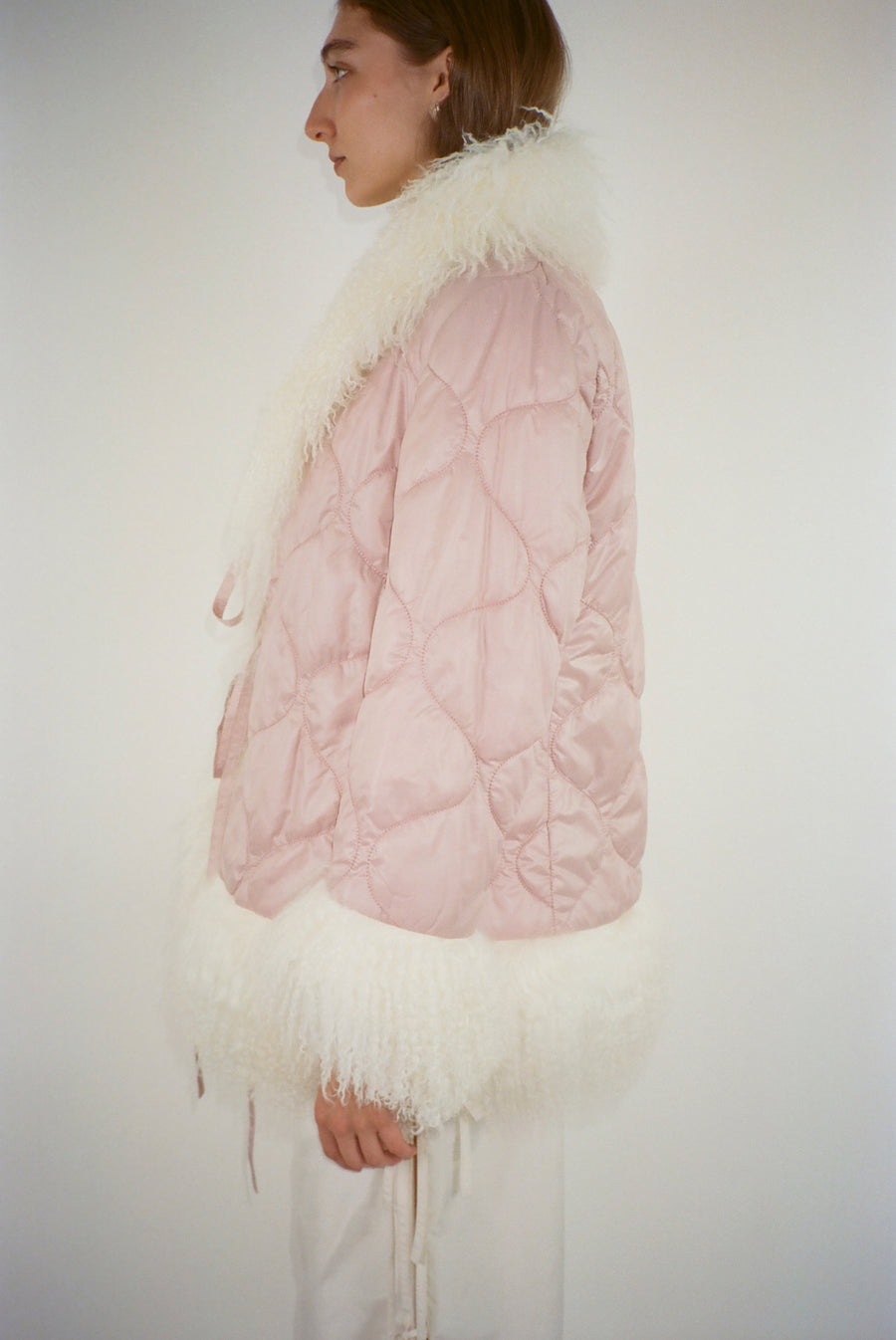 Quilted puffer jacket in pink trimmed in white shearling on model