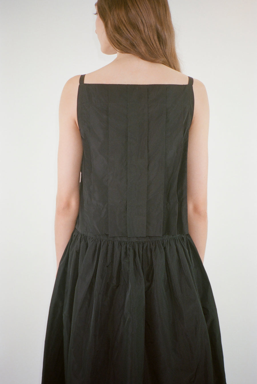 Midi length dress in black taffeta with buttons and cape detail at back on model