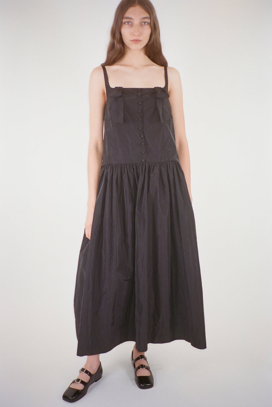 Midi length dress in black taffeta with buttons and cape detail at back on model