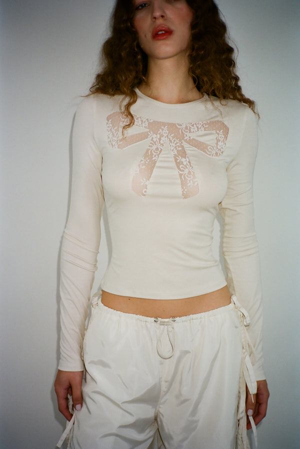 Long sleeve top in off white with lace cut out bow detail