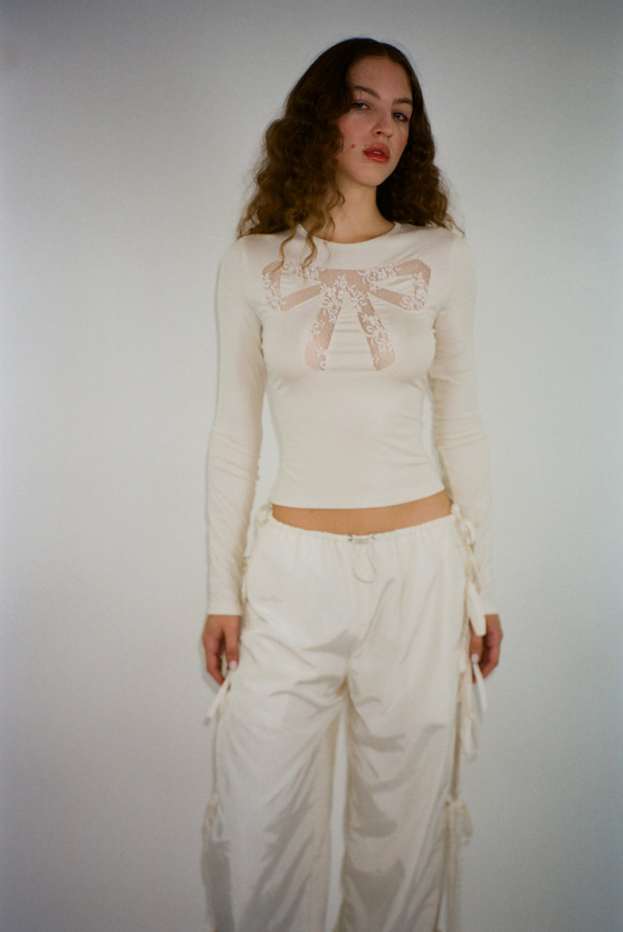 Long sleeve top in off white with lace cut out bow detail on model