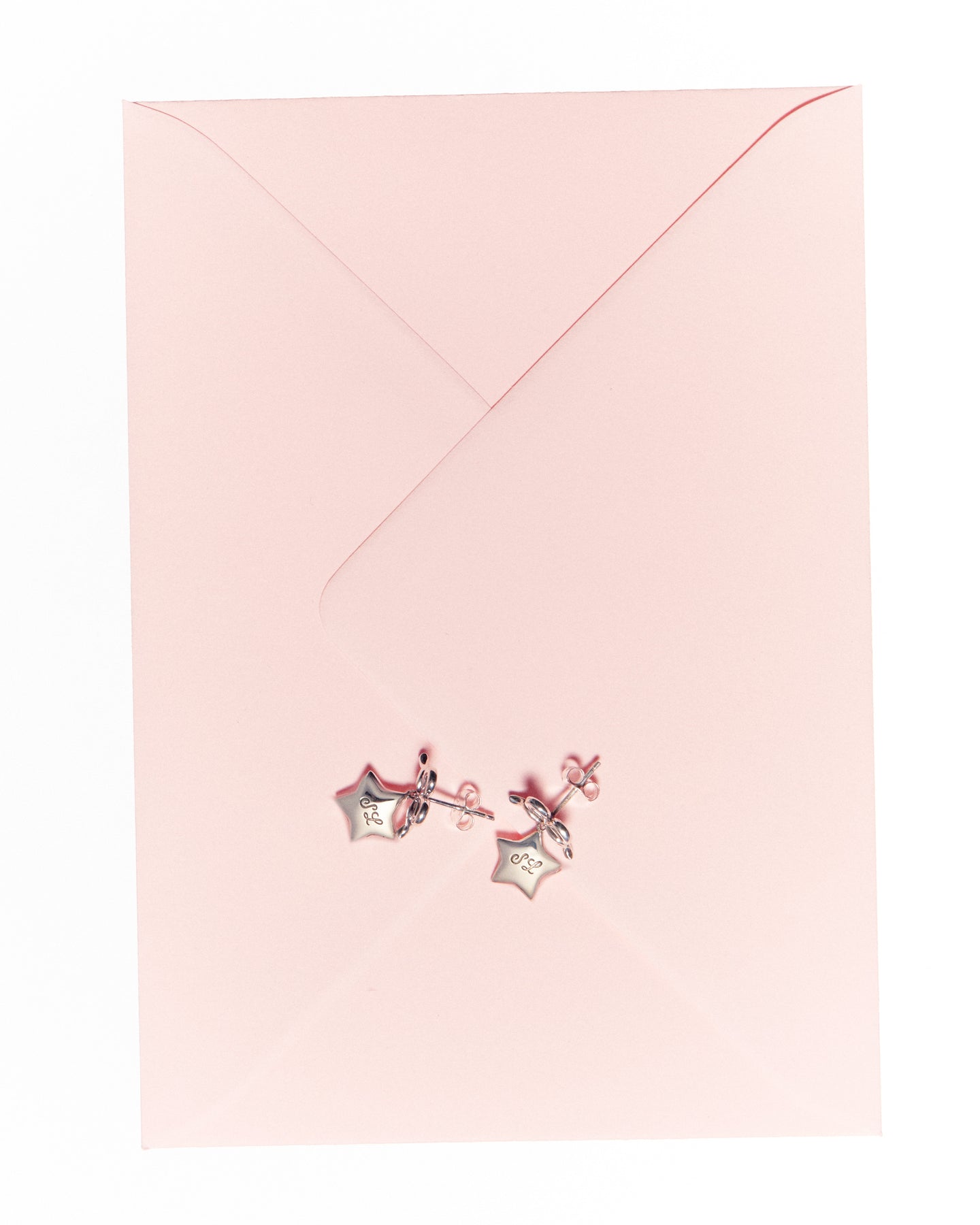 Bow earrings with star drop in silver on a pink envelope