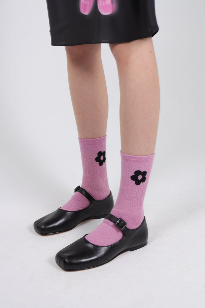 Tums pink crew length sock with black flower on either side on model