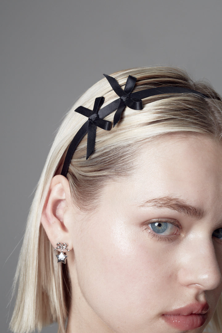 Black headband with two small bows on either side on model