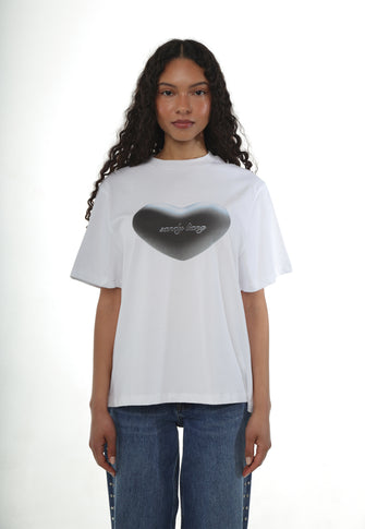 A woman wears a white tshirt with heart shaped graphic printed on with a pair of blue jeans against a white background